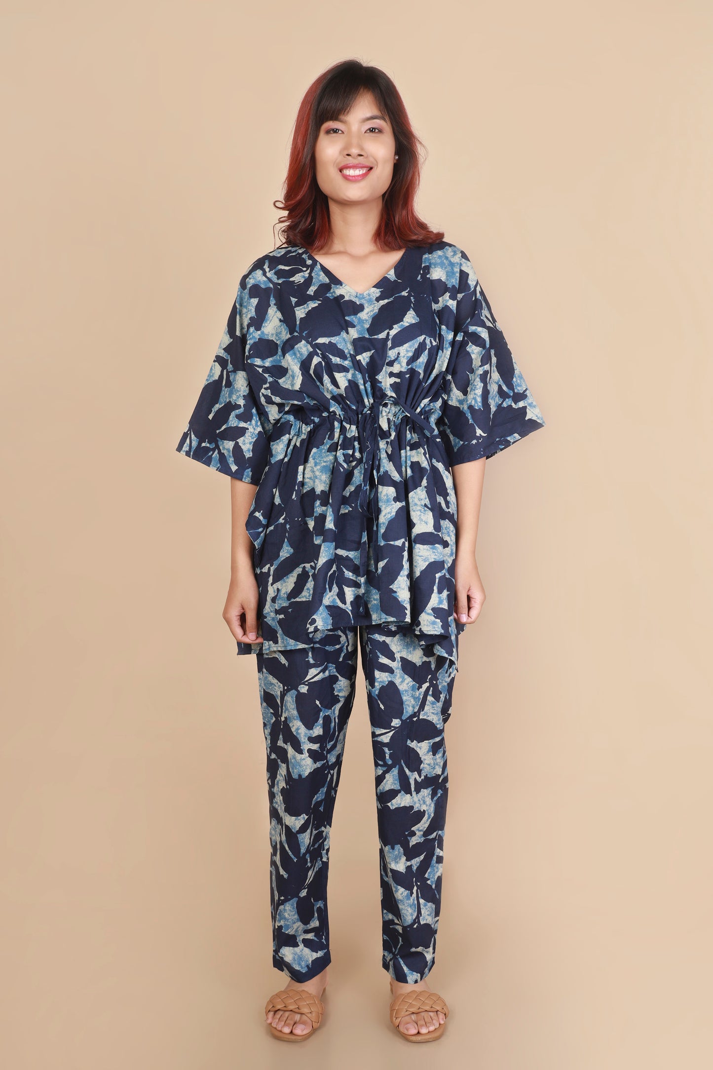 Woman wearing a navy blue floral patterned outfit on a beige background