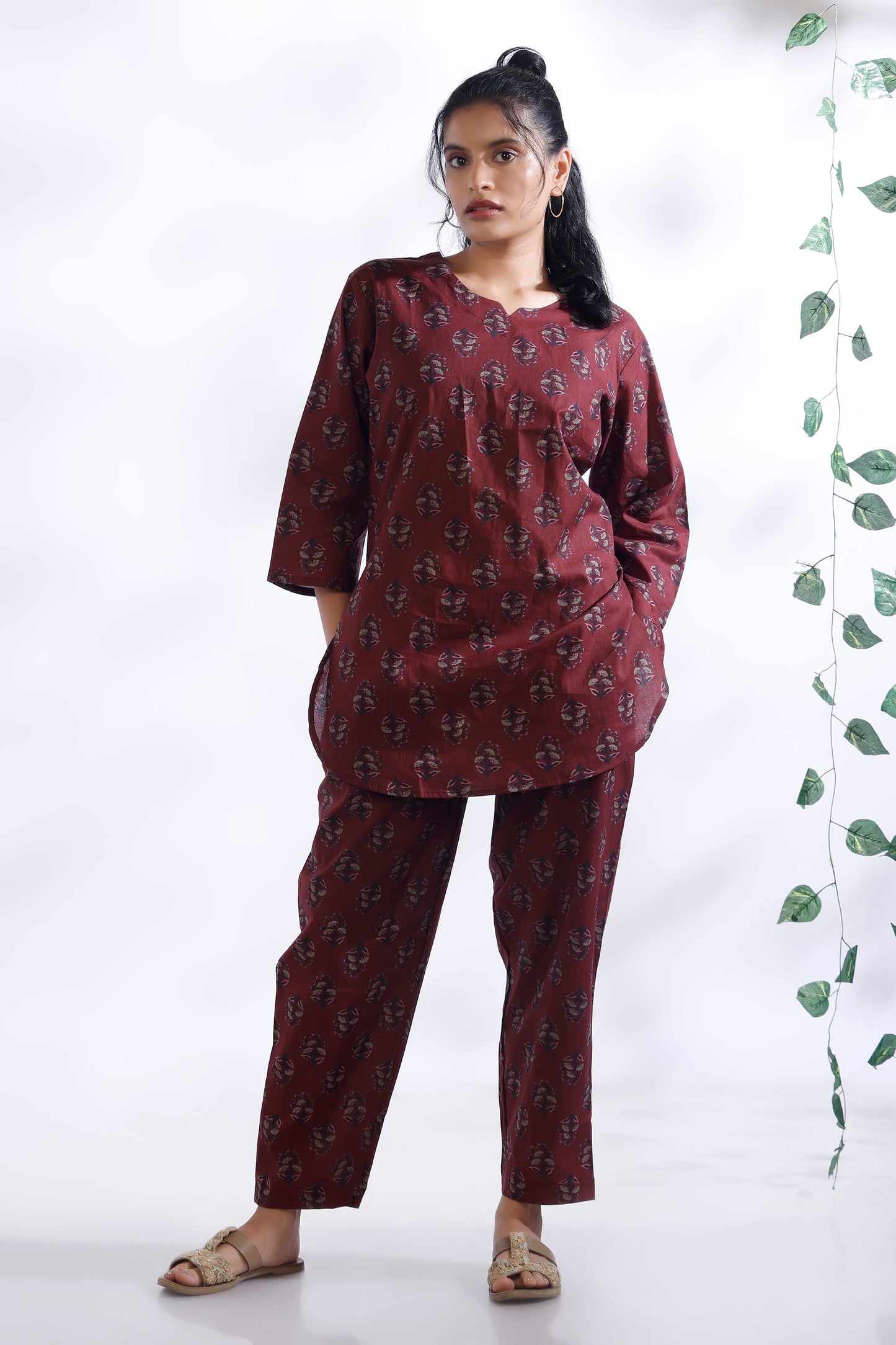 Woman wearing a maroon patterned outfit against a white background
