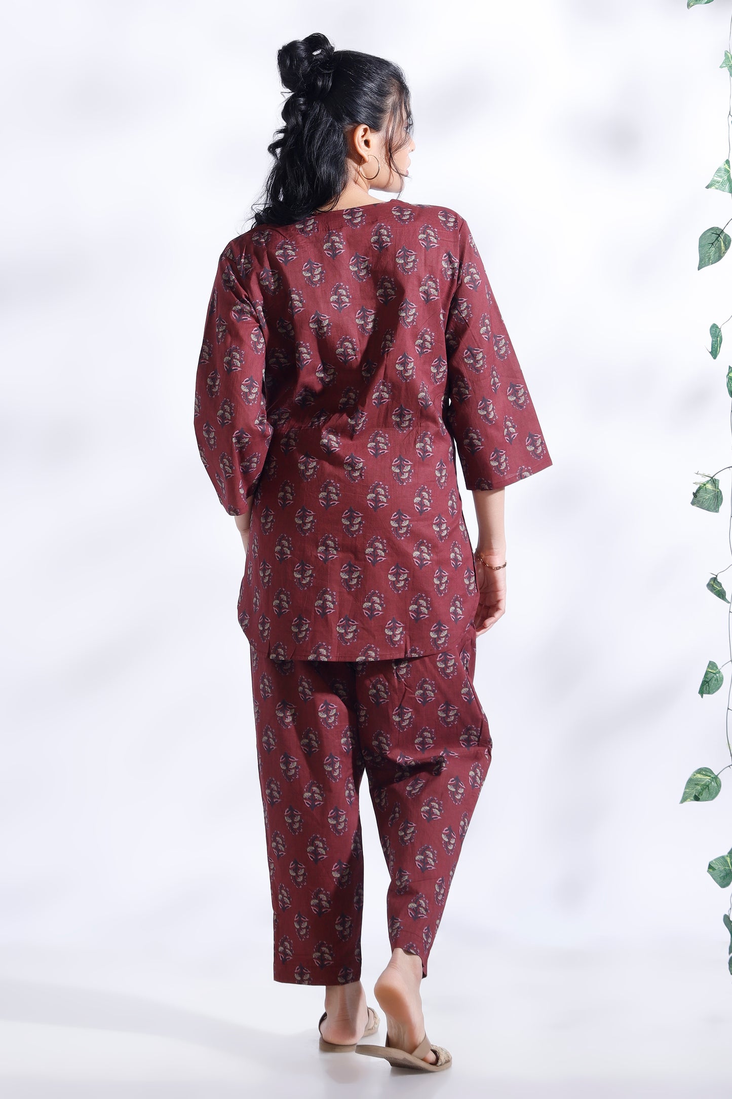 Person wearing a maroon patterned outfit on a white background