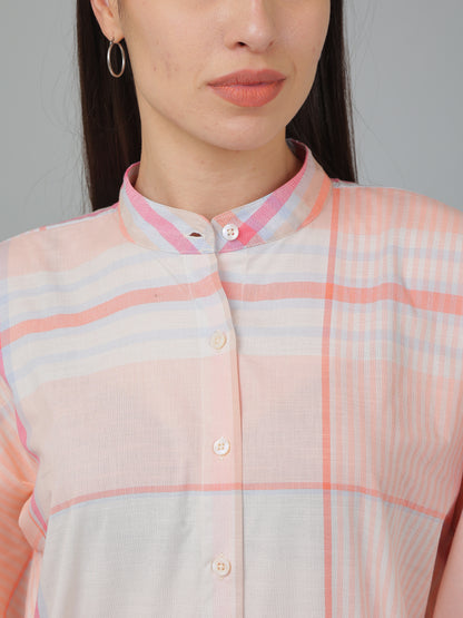 Person wearing a light pink and white checkered shirt with a neutral background