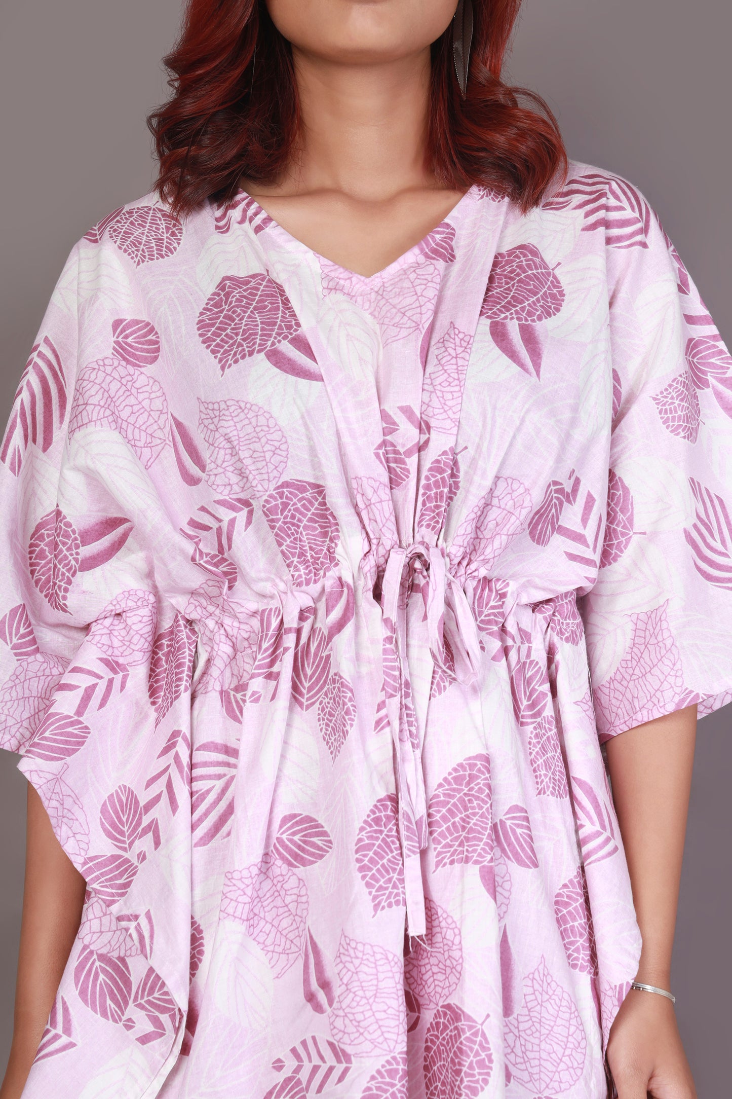 Woman wearing a white dress with pink floral patterns on a plain background