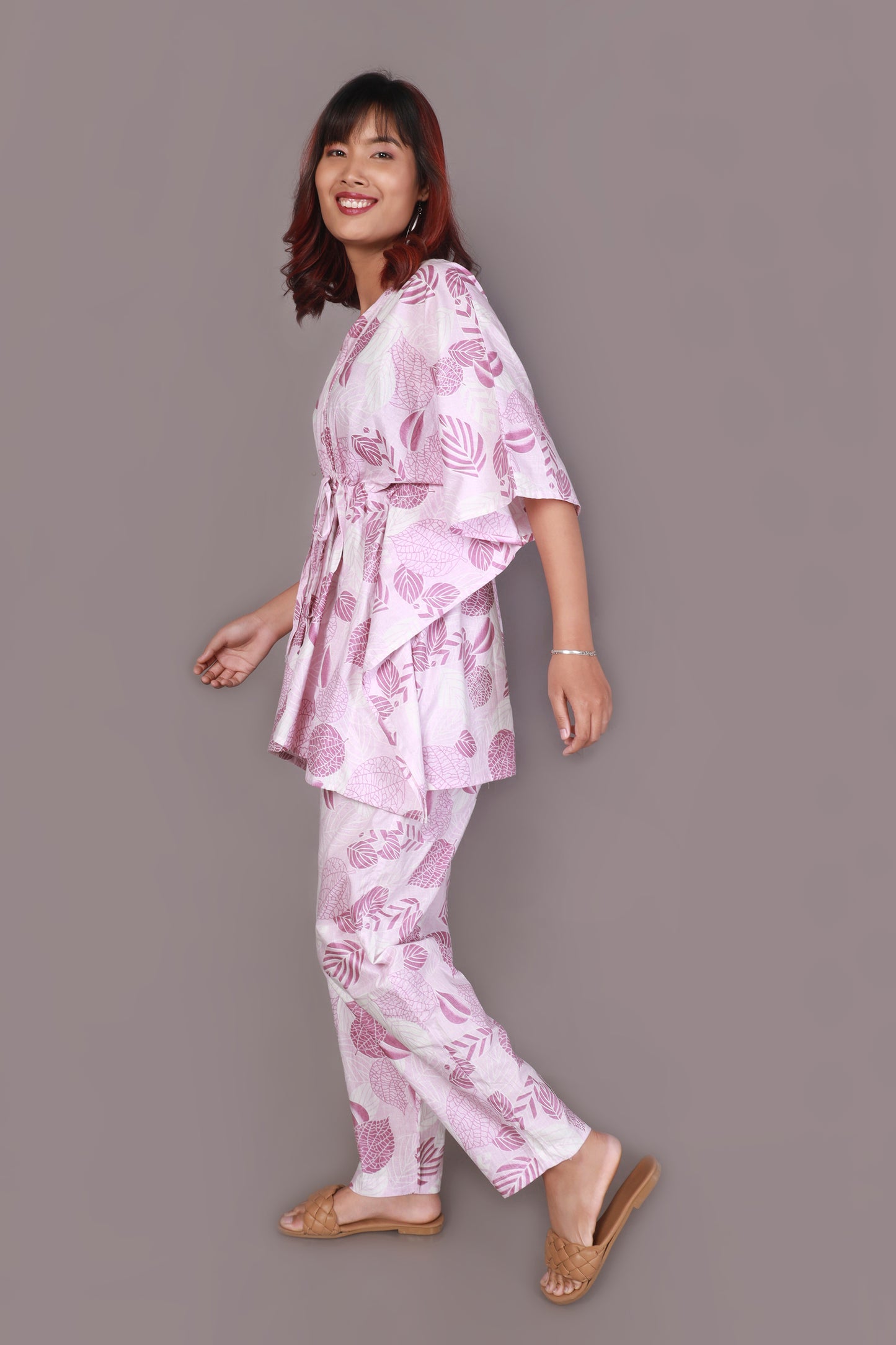 Woman wearing a pink floral pajama set against a gray background