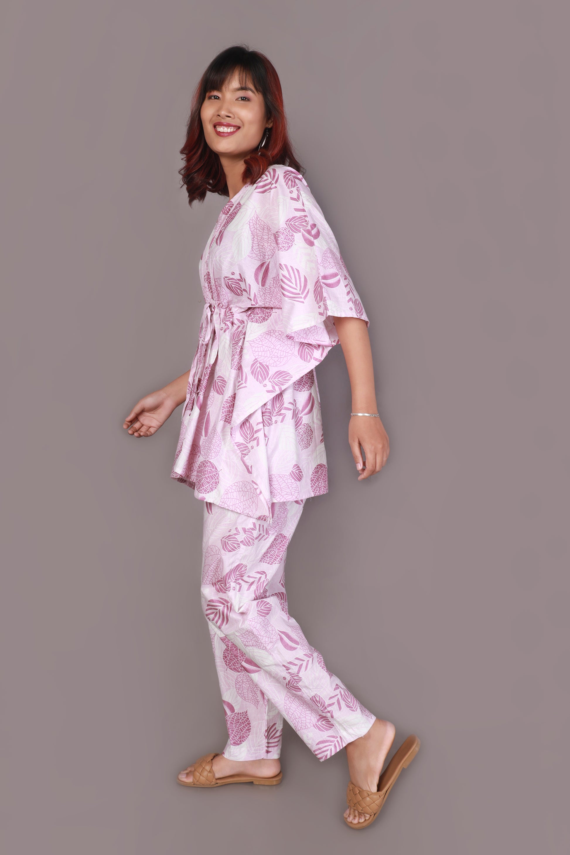 Woman wearing a pink floral pajama set against a gray background