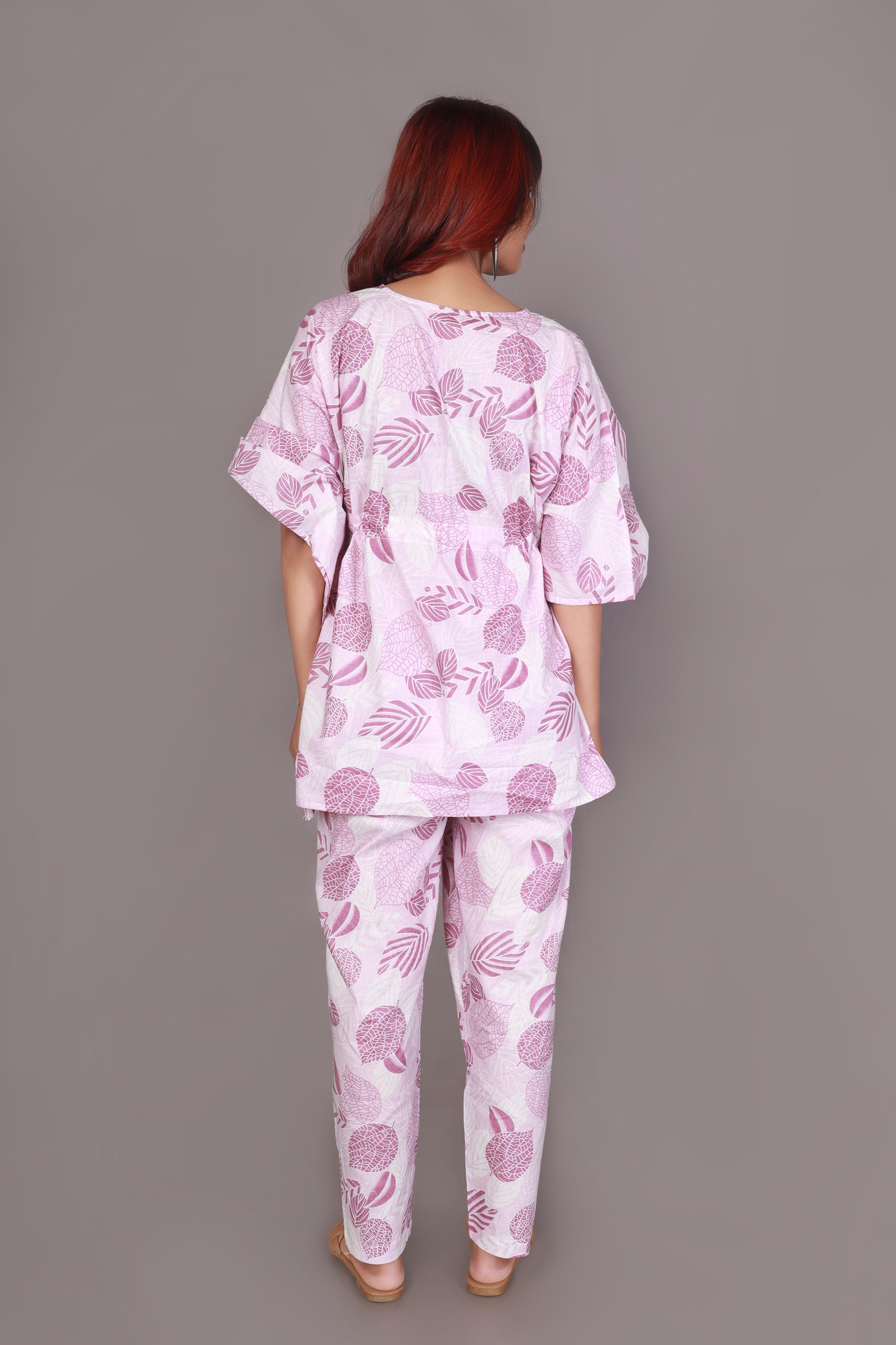 Person wearing a pink and white patterned outfit against a gray background