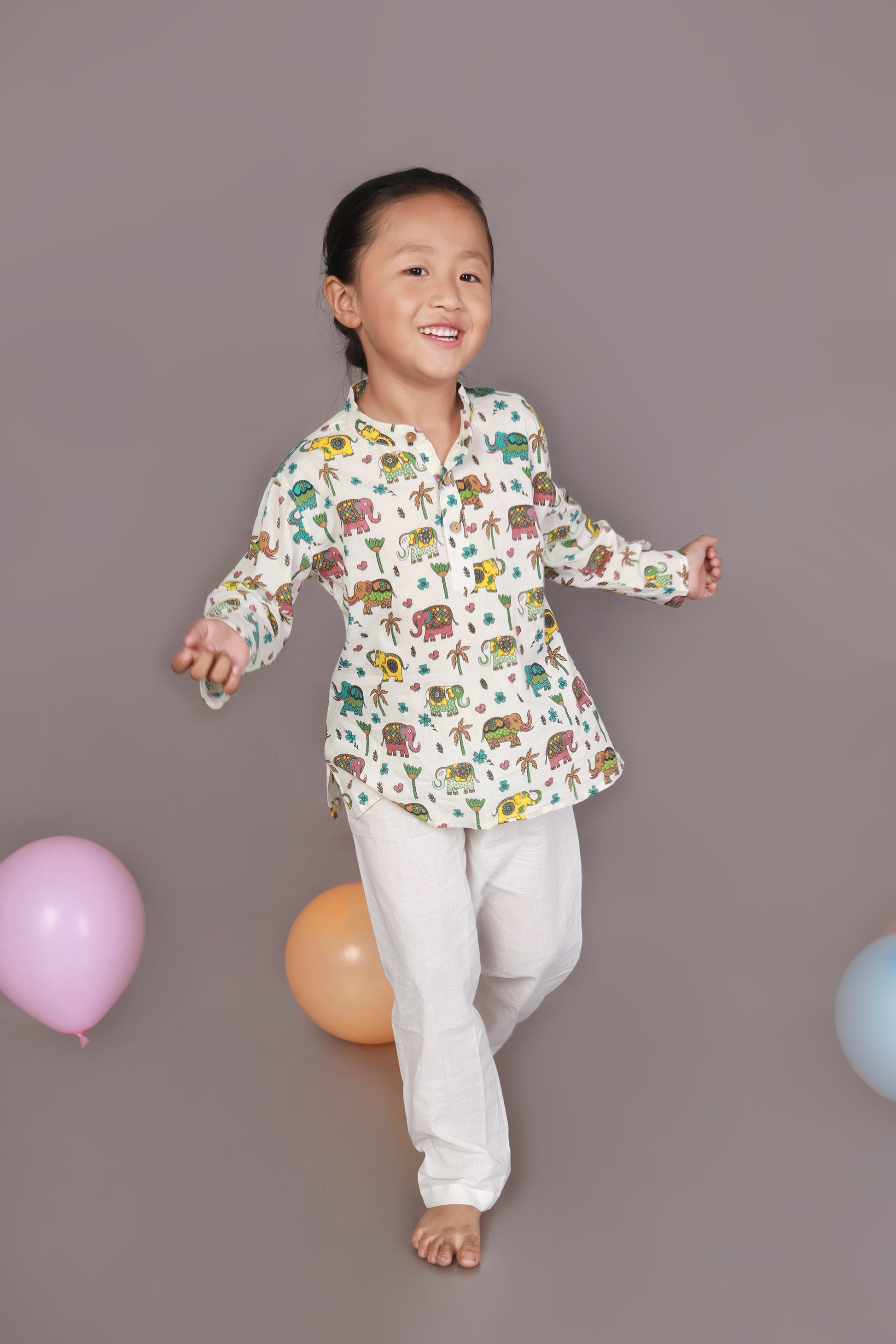 Child wearing a colorful elephant animal patterned Kurta and white pants 