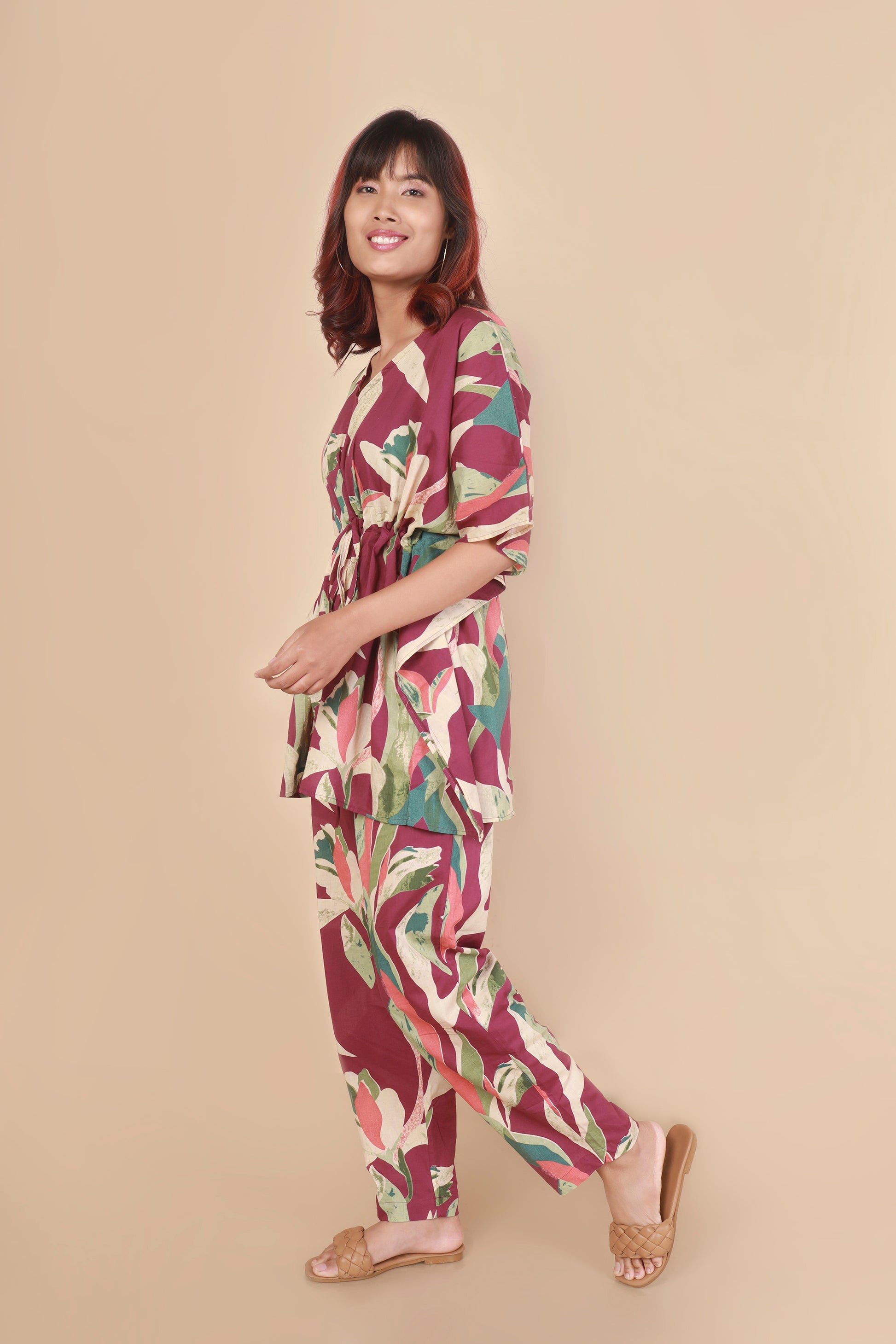 Woman wearing a colorful floral jumpsuit on a beige background