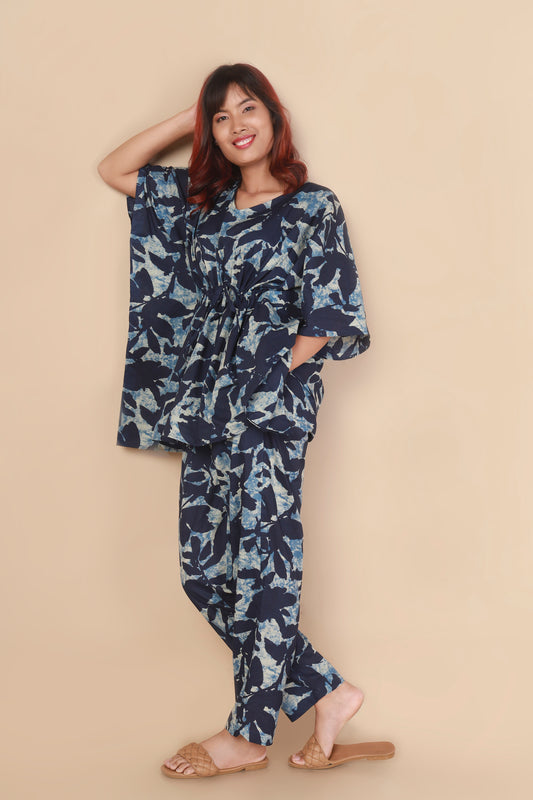 Woman wearing a blue floral jumpsuit against a beige background