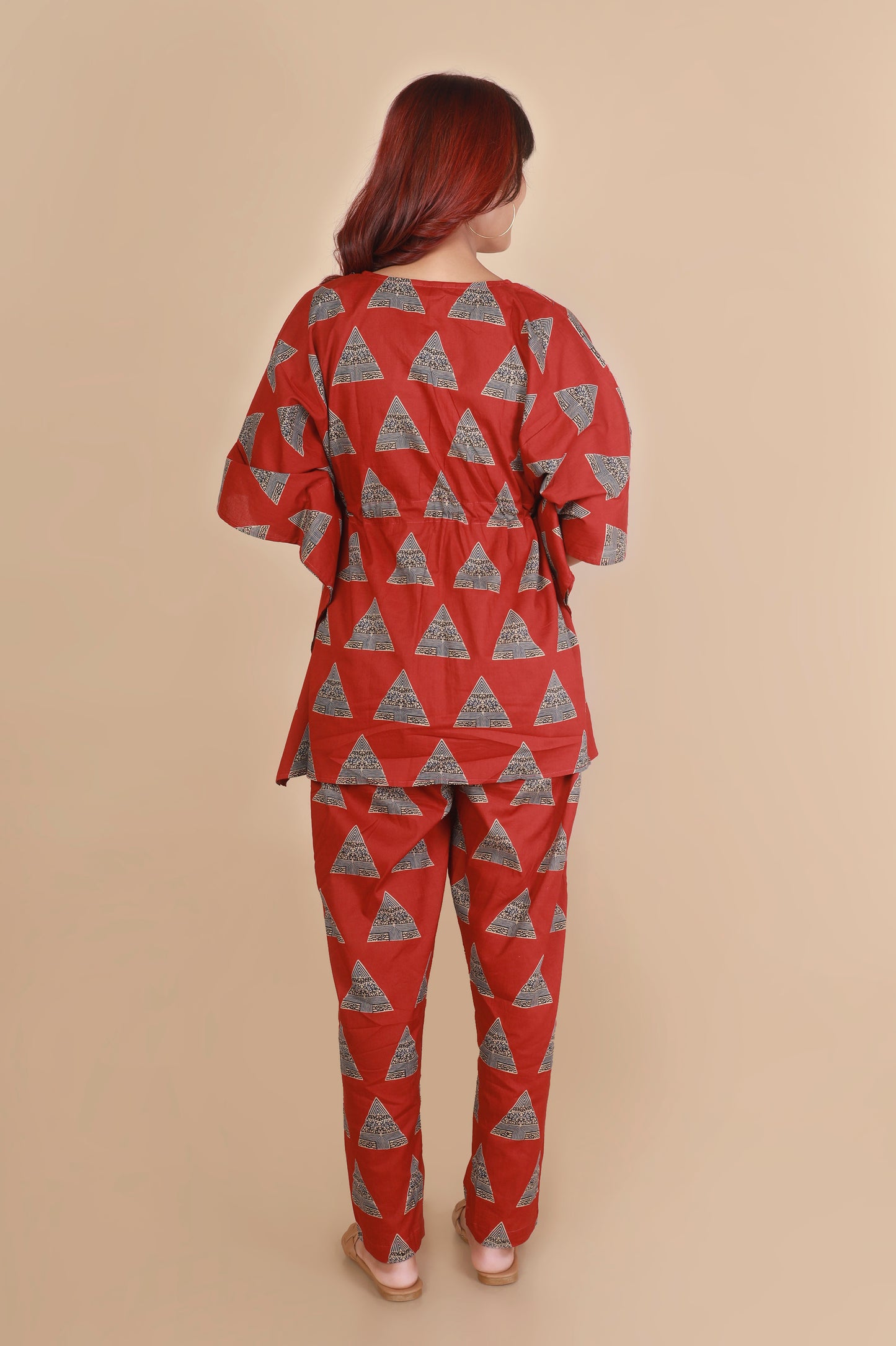 Person wearing a red and gray triangle-patterned outfit on a beige background