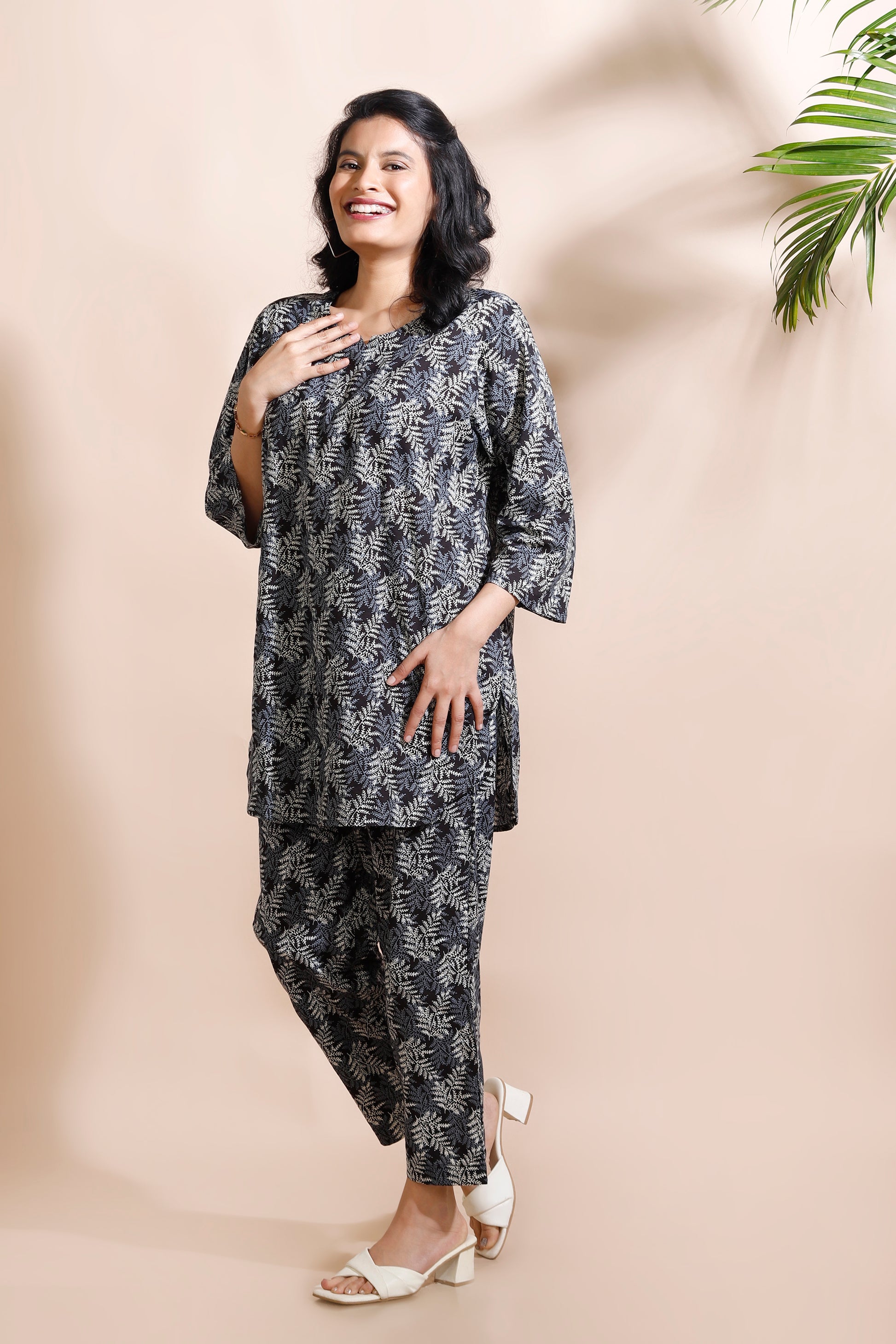 Woman wearing a black and white patterned outfit against a beige background