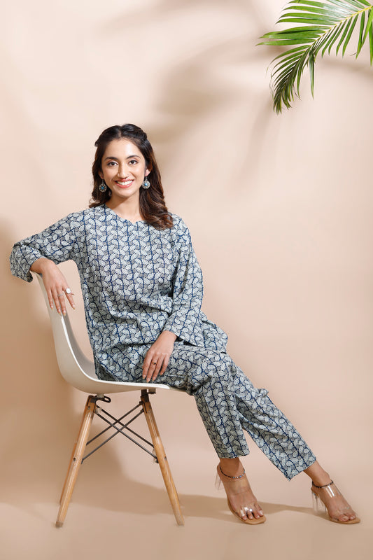 Woman in a floral outfit sitting on a chair with a beige background