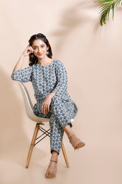 Woman sitting on a chair wearing a blue floral outfit against a beige background