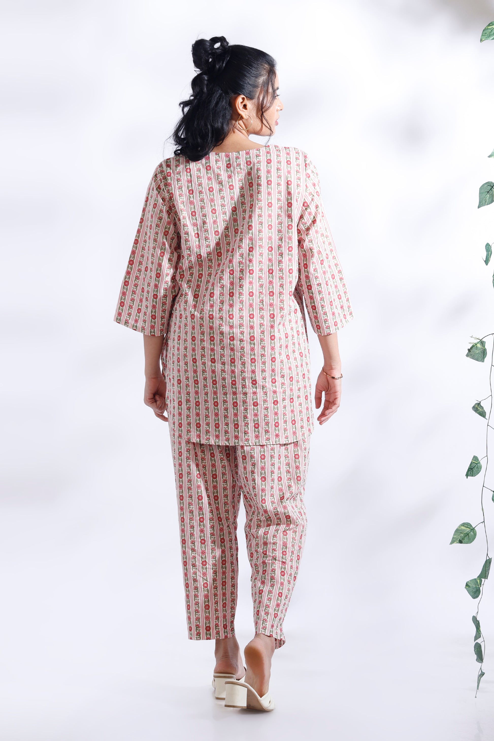 Woman wearing a matching top and pants set with a white background