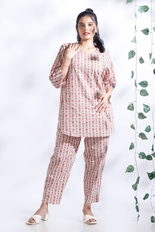 Woman wearing a matching set of top and pants with a white background and green leaves.