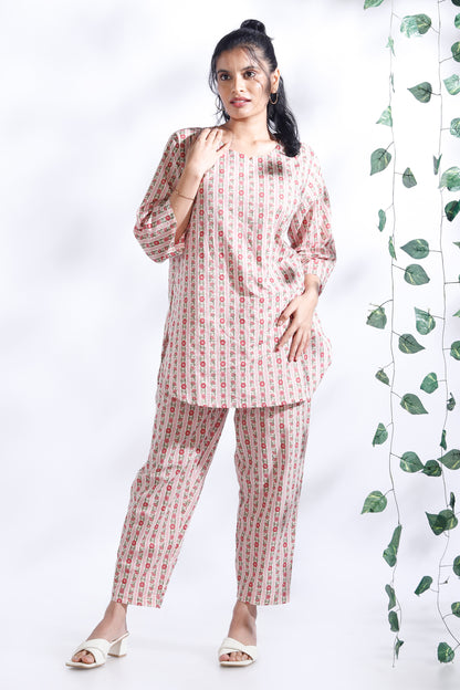 Woman wearing a matching set of kurta and pants with a white background and green leaves.