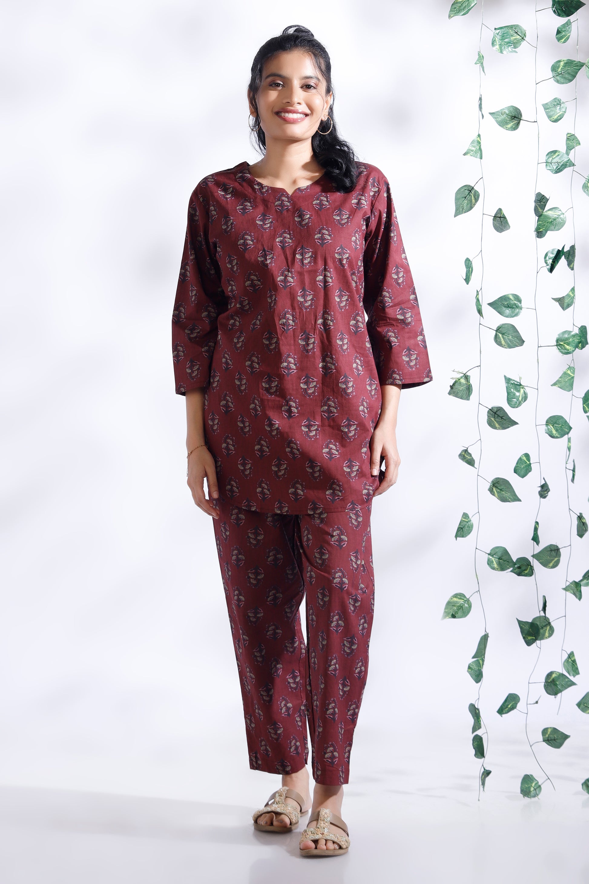 Woman wearing a maroon printed outfit with a white background