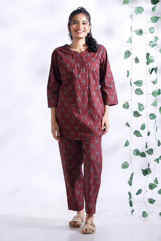 Woman wearing a maroon printed outfit with a white background