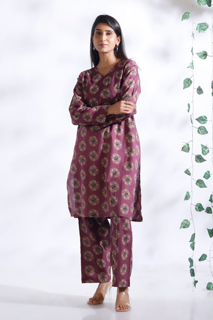 Woman wearing a purple floral kurta with pants against a white background
