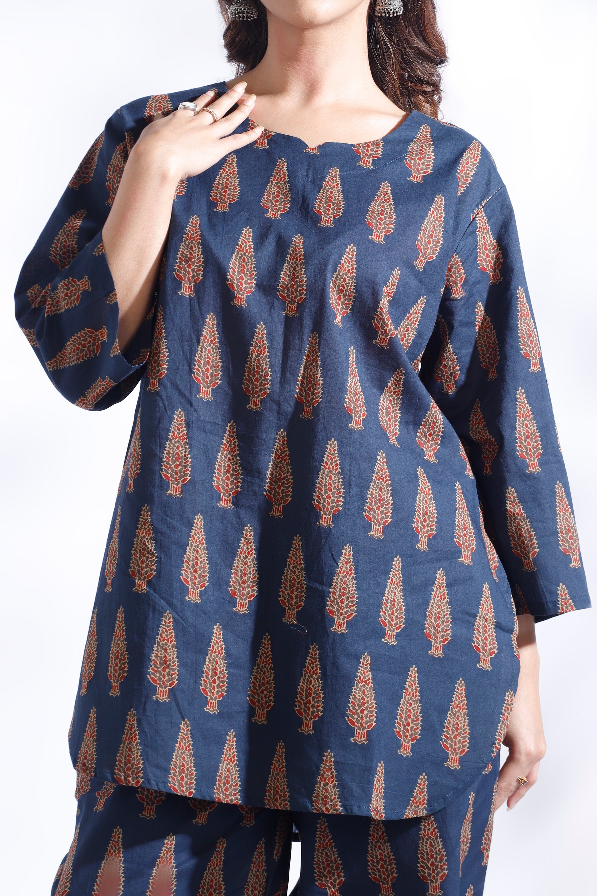 Navy blue top with brown leaf pattern worn by a model on a white background