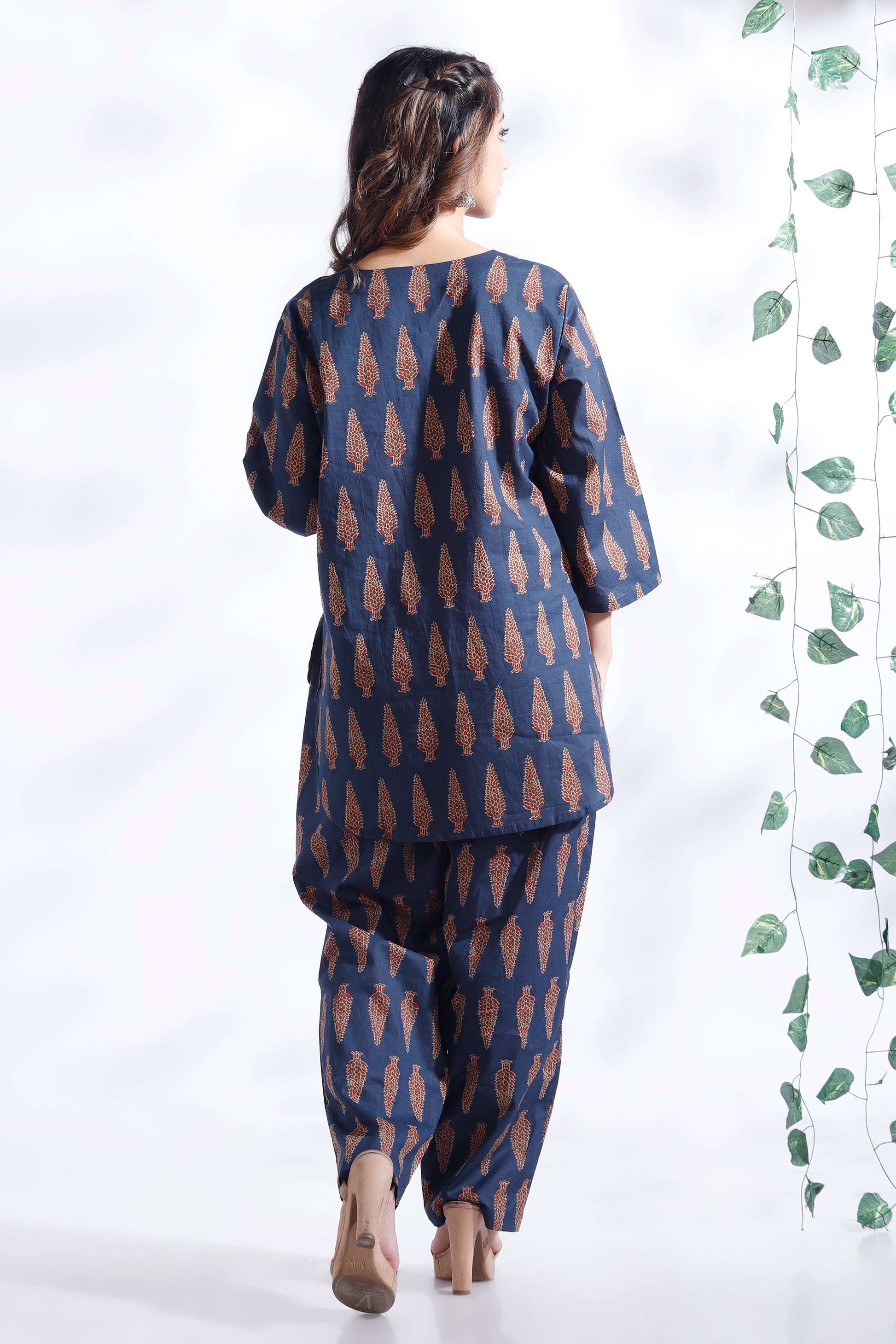 Woman wearing a blue and brown patterned outfit with a white background