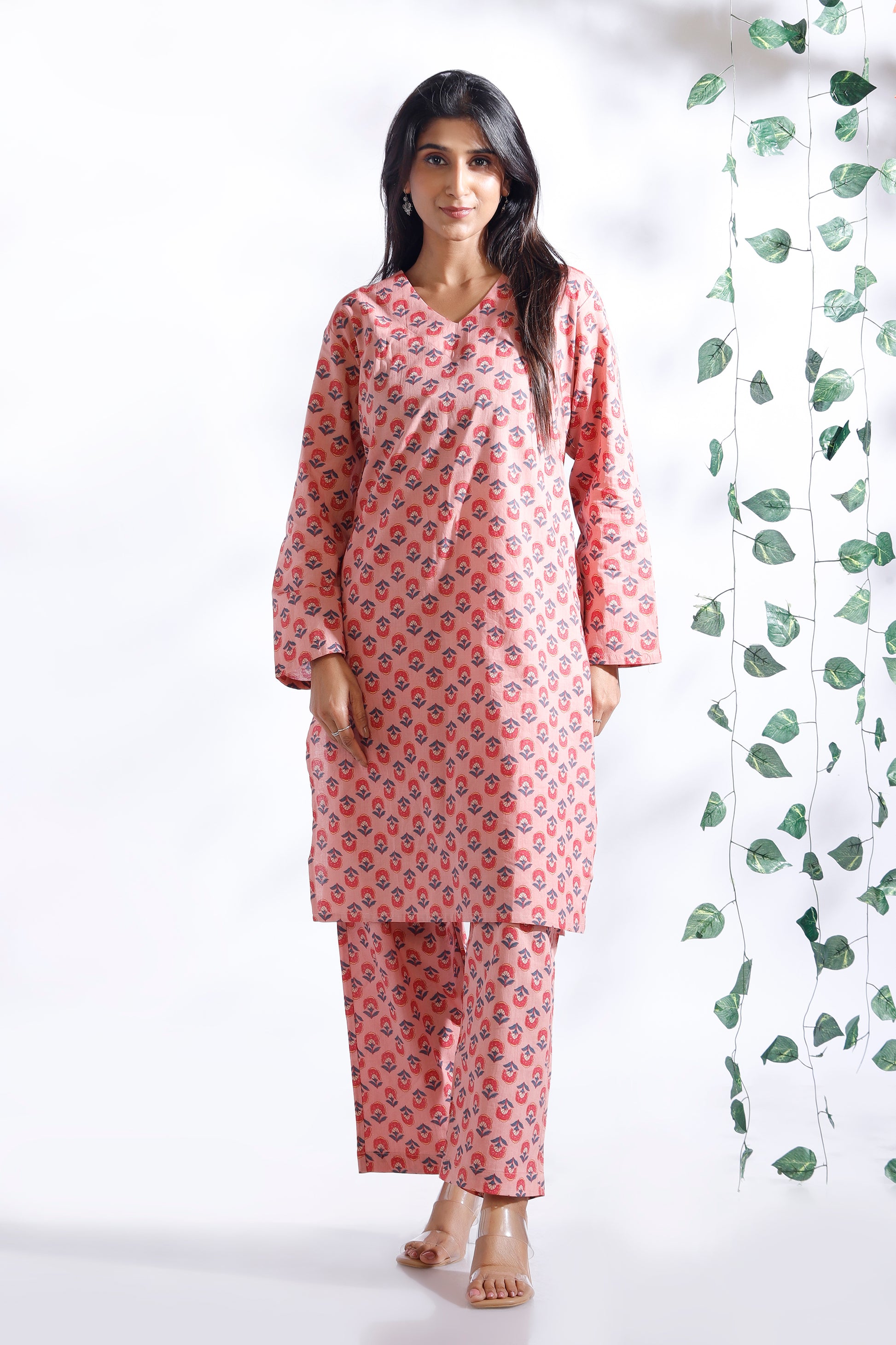 Woman wearing a pink floral kurta with matching pants against a white background