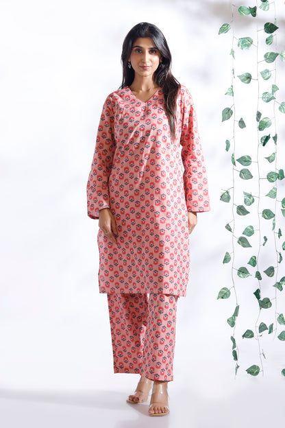 Woman wearing a pink floral kurta with matching pants against a white background