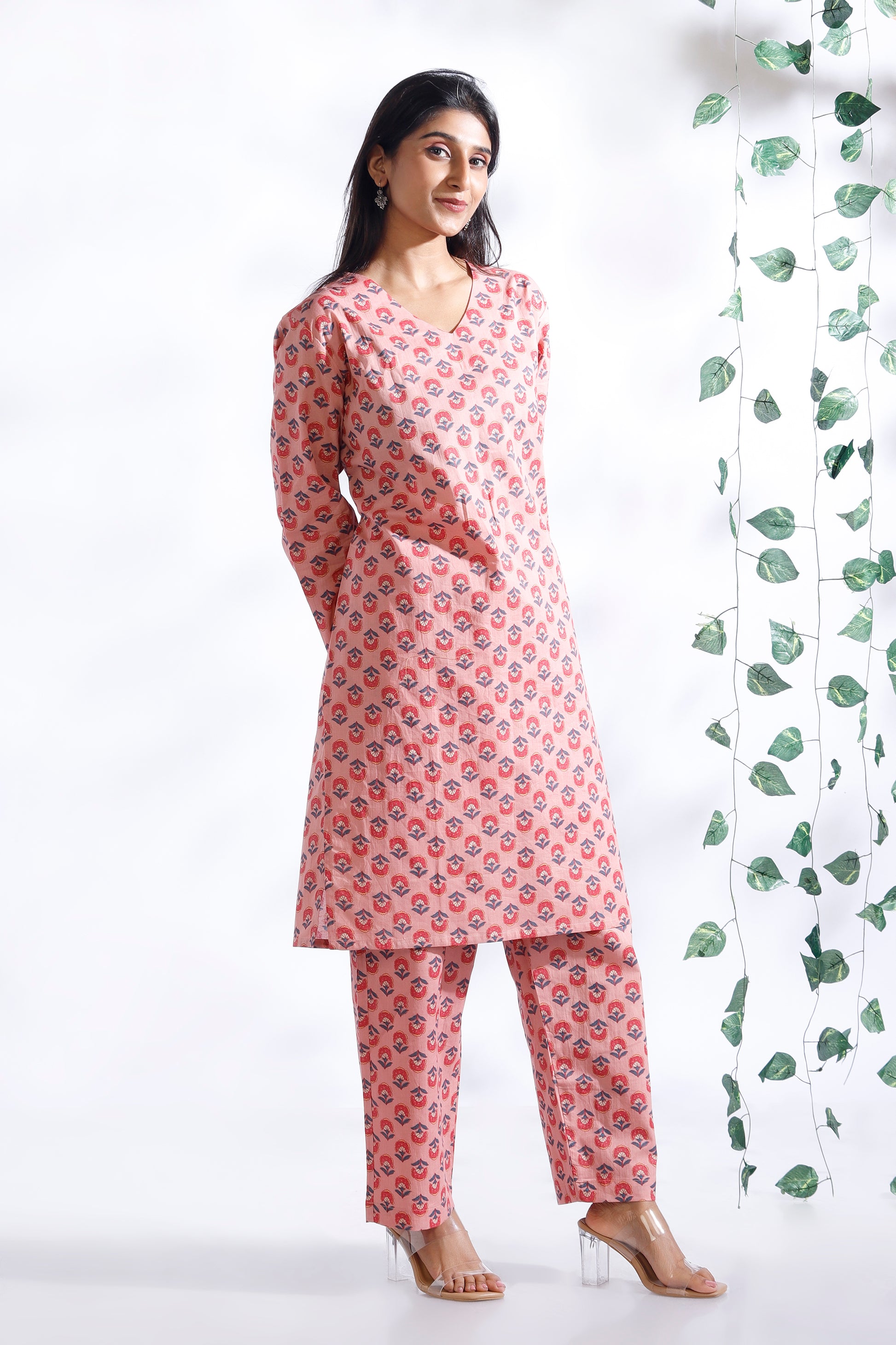 Woman wearing a pink floral kurta with pants against a white background