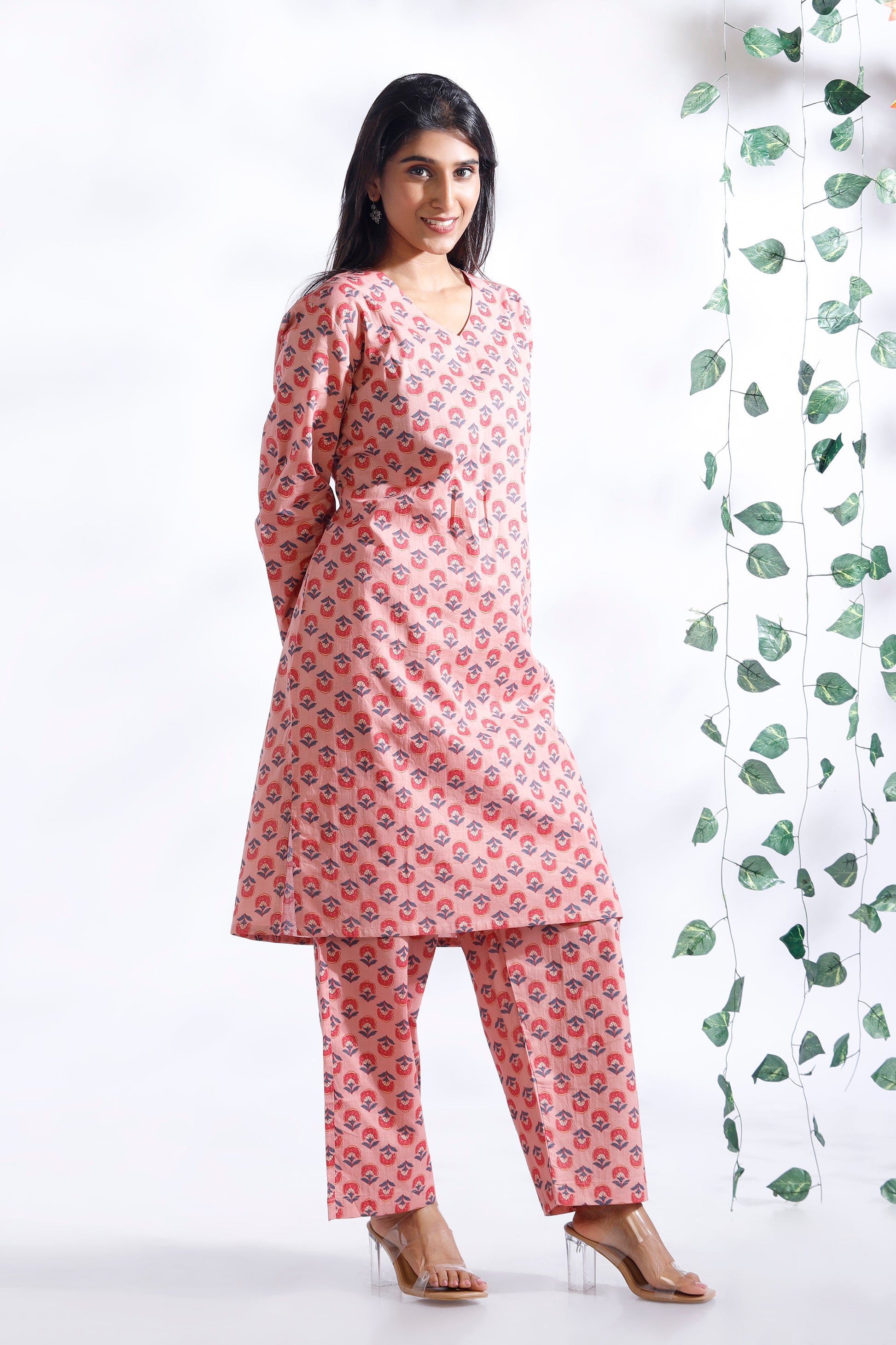 Woman wearing a pink floral kurta with pants against a white background