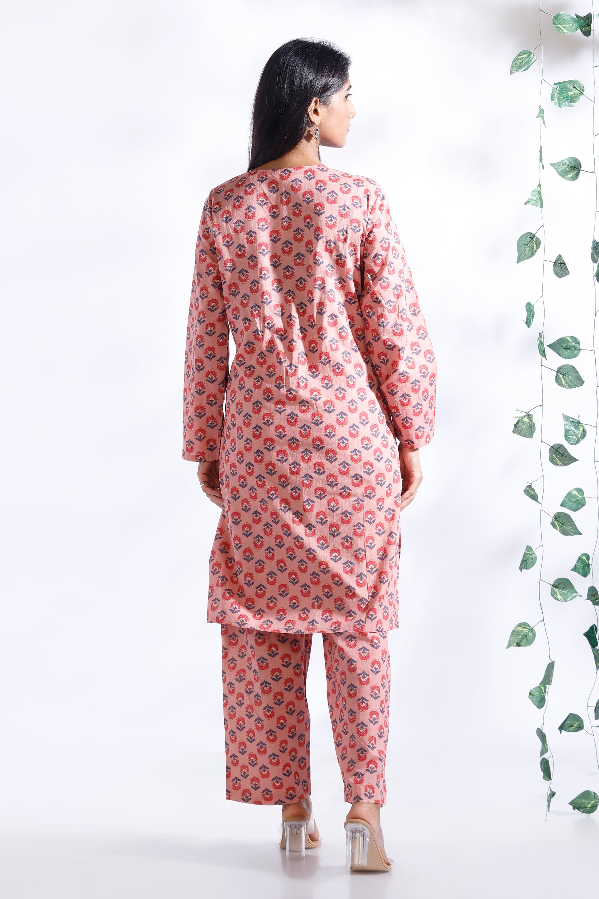 Woman wearing a pink floral kurta with pants on a white background