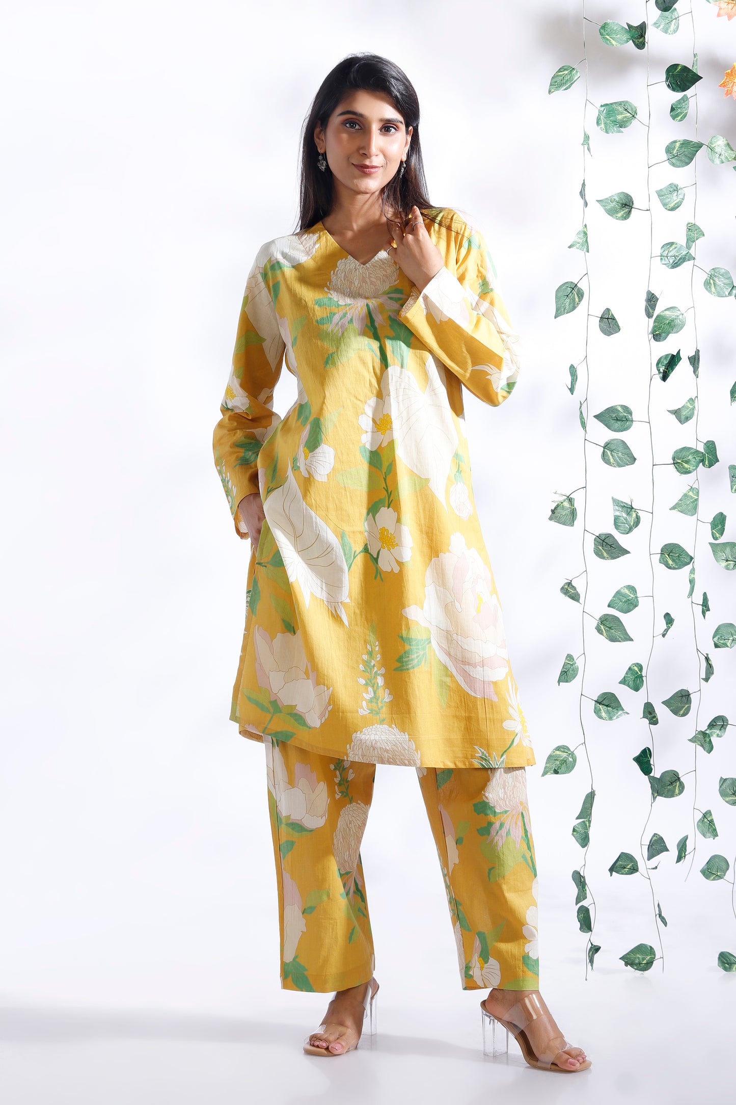 Woman wearing a yellow and white floral outfit with a white background
