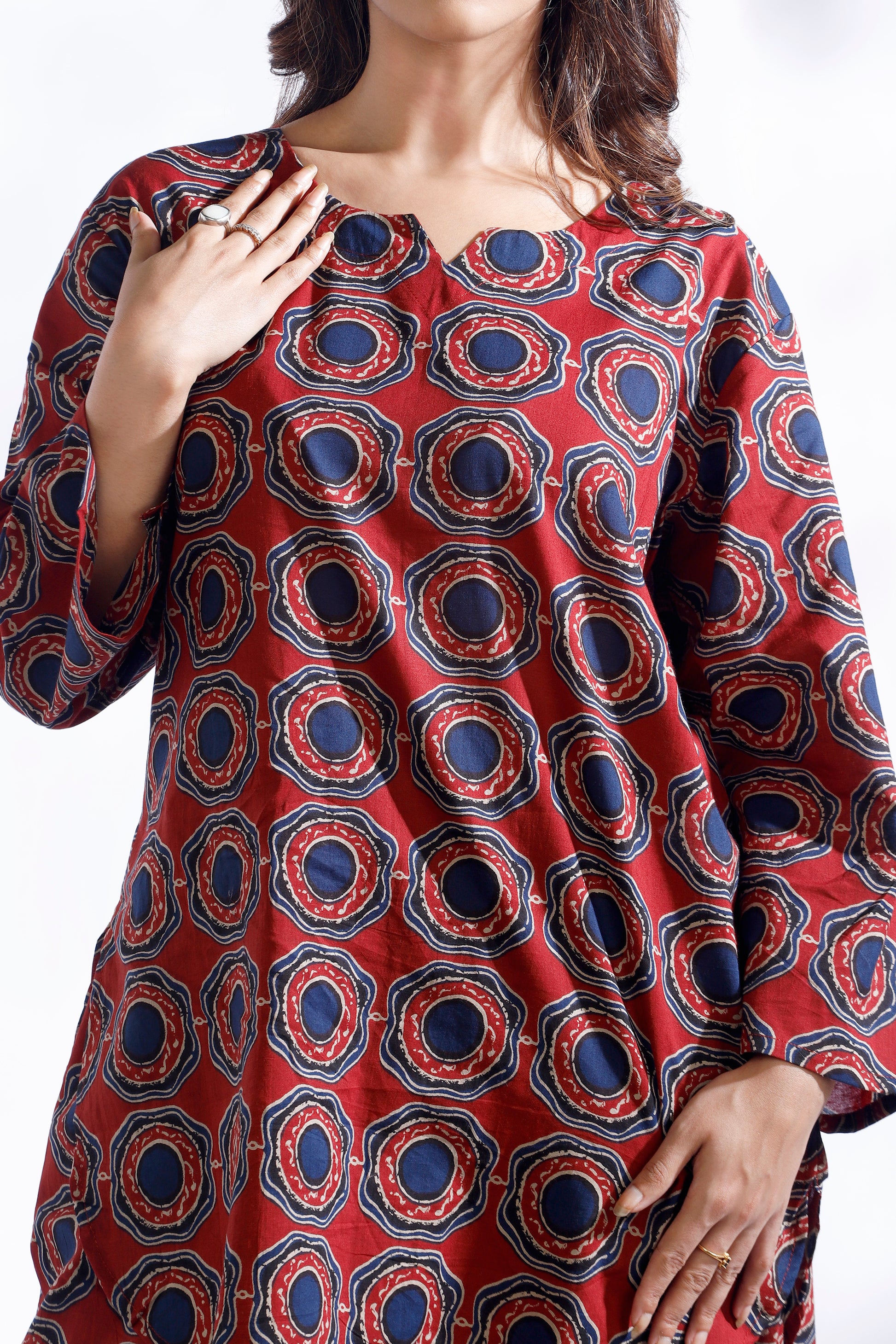 Red patterned dress worn by a person on a white background