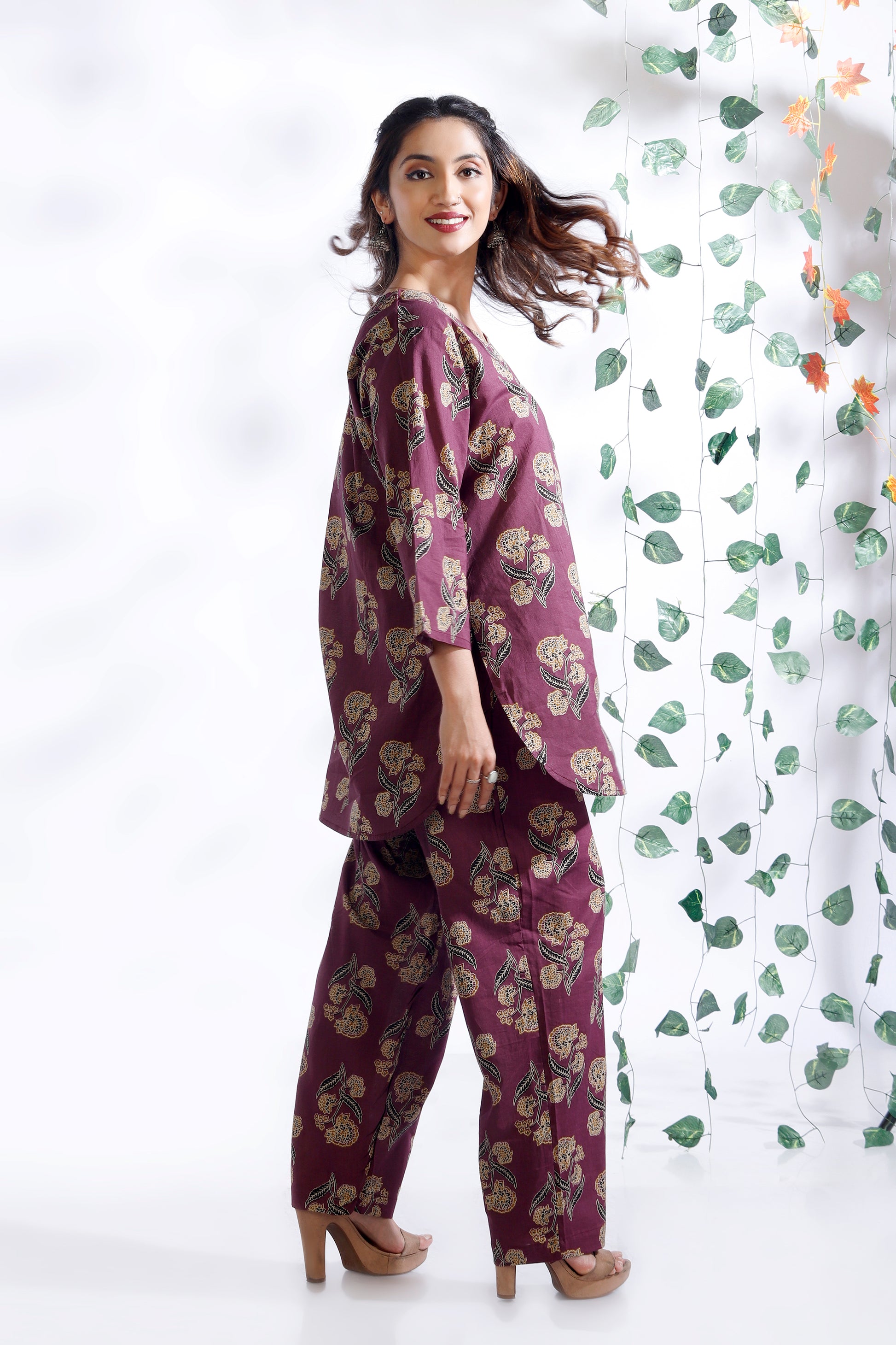 Woman wearing a purple floral outfit with a white background