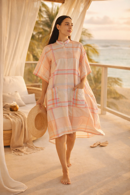Woman in a plaid dress standing on a balcony with ocean view