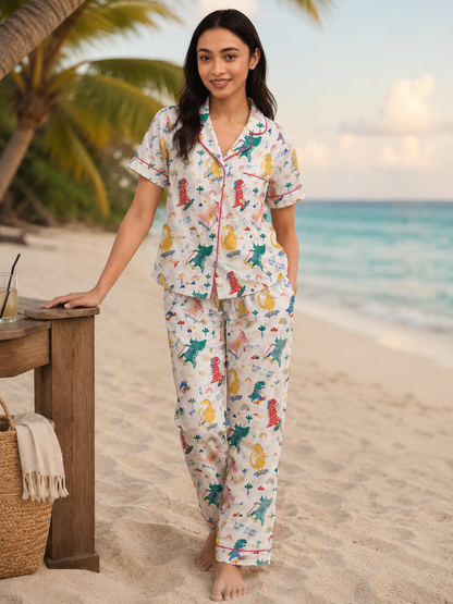 Woman wearing a colorful pajama set on a beach with palm trees and ocean in the background.